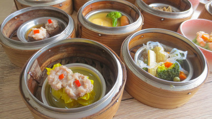 close up of set steamed dim sum dumplings in basket, chinese traditional food
