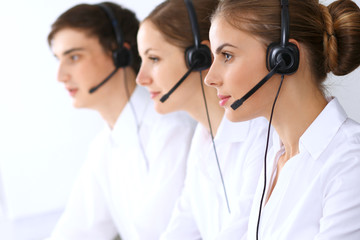 Call center operators at work. Focus at beautiful business woman in headset