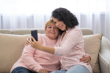 Obraz premium Asian senior woman and daughters taking picture with mobile phone