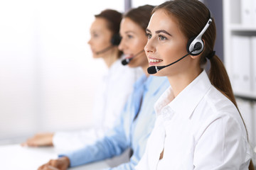 Call center. Group of operators at work. Focus on beautiful business woman in headset
