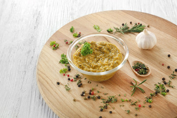 Tasty sauce in bowl with spices on wooden board