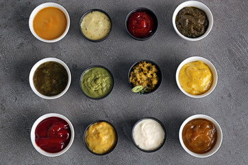 Different tasty sauces in bowls on grey table