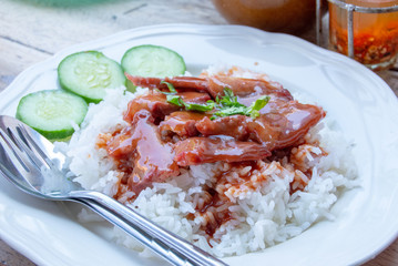 Red pork with rice and cucumber on a plate.