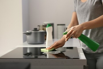 Woman cleaning stove in kitchen