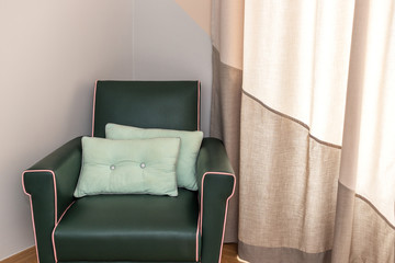 Soft leather chair in the room for rest, with pillows.