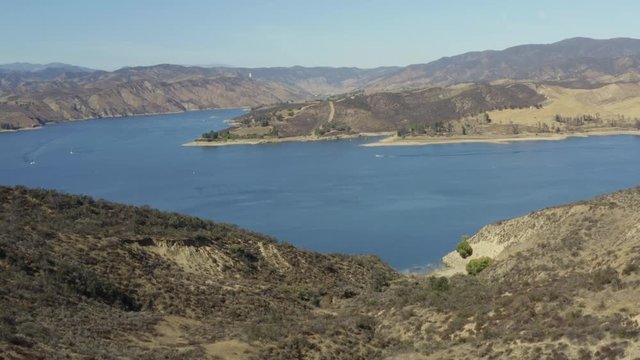 A blue lake in between hills with power boats and kayaks
