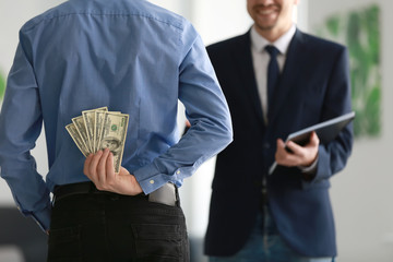 Man holding bribe for businessman behind back. Corruption concept