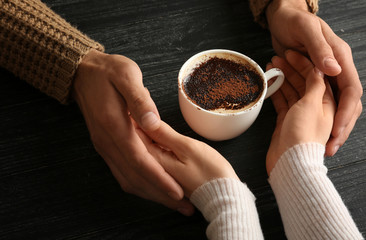 Loving young couple with cup of coffee on wooden background