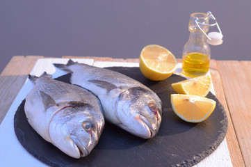  dorado fish on a black plate with lemon 