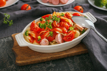 Delicious pasta with sausage and sauce in ceramic dish on table