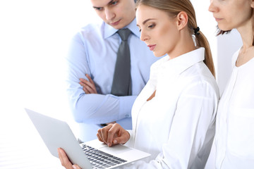 Obraz premium Group of business people using laptop computer while standing in office. Meeting and teamwork concept