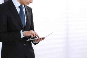 Unknown businessman holding digital tablet in office