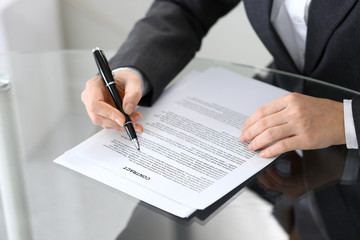 Close-up of female hands with pen over document of contact, business concept