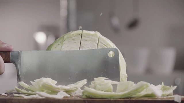 Cutting cabbage with kitchen ax on the wood. Slow motion 240 fps