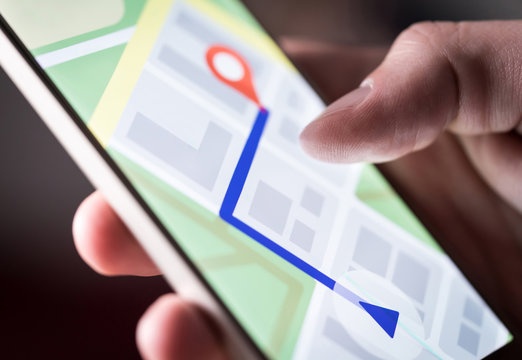Map application in smartphone. Man navigating in city with mobile phone. Person using cellphone and searching hotel with navigation app. Macro close up of screen.
