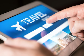 Travel search engine and website for holidays. Man using tablet to look for cheap flights and...