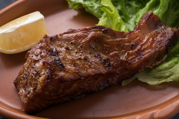 Grilled sturgeon on a plate with lemon. Closeup