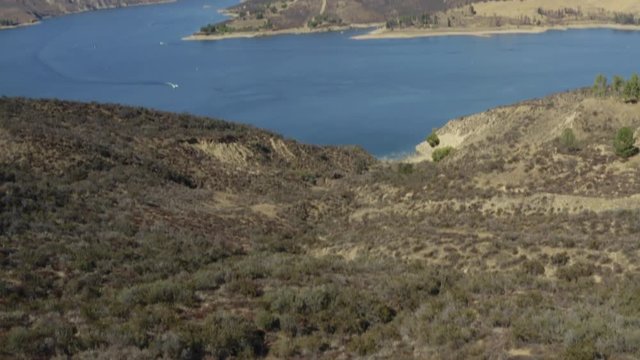 A blue lake in between hills with power boats and kayaks