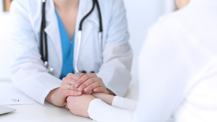 Medicine doctor hand reassuring her female patient closeup. Medicine, comforting  and trusting concept in health care