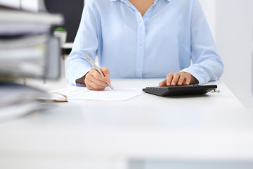 Unknown female bookkeeper or financial inspector calculating or checking balance, making report, close-up. Internal Revenue Service at work with financial document. Tax and audit concept