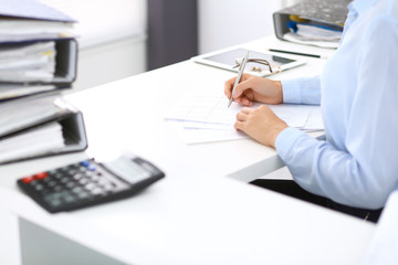 Unknown female bookkeeper or financial inspector calculating or checking balance, making report, close-up. Internal Revenue Service at work with financial document. Tax and audit concept