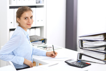 Woman bookkeeper or financial inspector calculating or checking balance, making report. Internal Revenue Service at work with financial document. Tax and audit concept