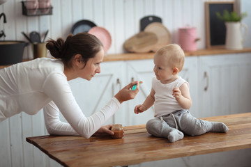 Fototapeta premium first feeding, mother with spoon feeds her son