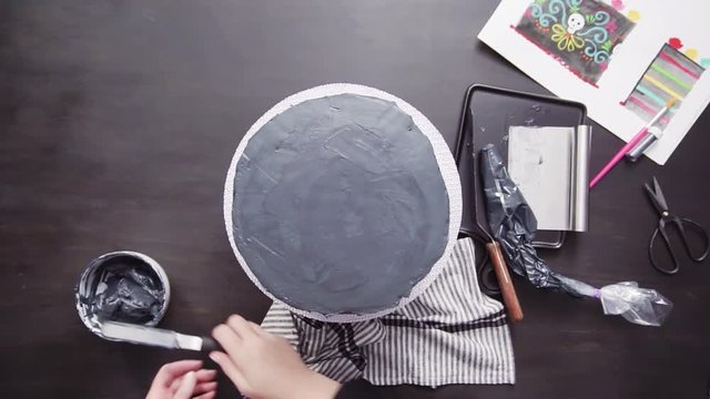 Step by step. Flat lay. Baker frosting multilayer chocolate cake with a black italian buttercream frosting.