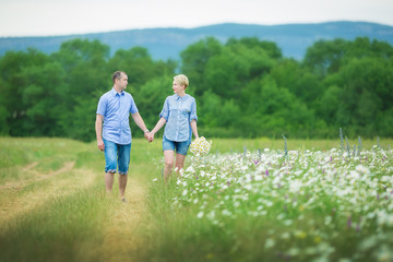 Romantic couple hugging and breathing fresh air in a warm field with daizy flowers