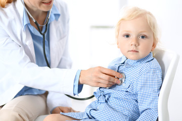 Doctor examining a little blonde girl with stethoscope.Medicine and healthcare concept