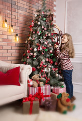 Obraz na płótnie Canvas Cute girl decorates the Christmas tree.