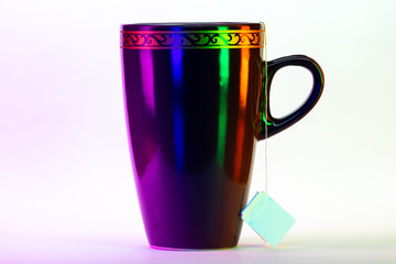 Cup of tea with tea bag from side with colorful lighting