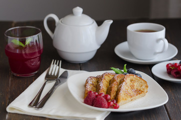Spanish Torrijas or french toasts with berries and icing sugar for breakfast in hotel restaurant.
