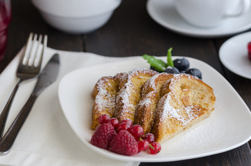 Spanish popular dessert Torrijas or french toasts, served with berries; currant berries, raspberries  and icing sugar. Popular breakfast in Spain.