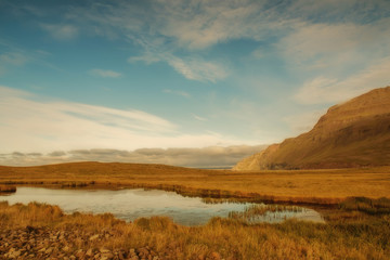 Icelandic landscape. The expanses of fields, a small lake on the background of mountains.
