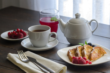 Spanish Torrijas or french toasts with berries and icing sugar for breakfast in hotel restaurant.
