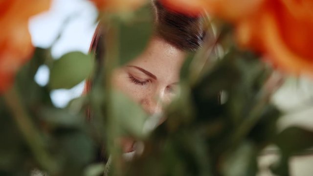 Portrait of an attractive girl through a bouquet of flowers. Close-up.