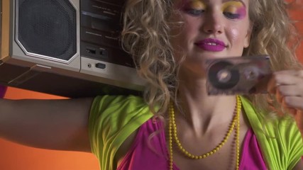 Lady from the 80s puts a cassette into the boombox and enjoys the music