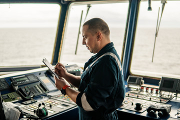 Marine navigational officer or chief mate on navigation watch on ship or vessel. He fills up...