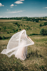 Fototapeta na wymiar The bride in nature with a long veil that flies in the wind.