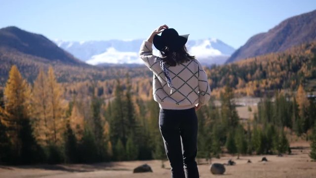 A woman with raised hands on top of a mountain looking at the view. The girl raises her hand up, noting the scenic landscape, enjoying nature, traveling adventure. Gorny Altai on the way to Mangolia