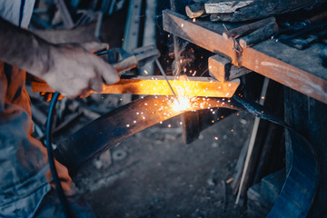 Manual welding in crafr workshop with sparks and smoke.