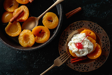 Peach dessert with cinnamon, cream and cherry.