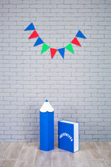 Studio shoot of school book pencil colorful flags on grey brick wall. School study decorations.On...