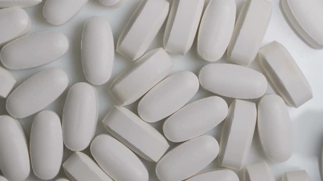 Pills rotate on white background. Medicine, sport supplement, creatine, hmb, bcaa, amino acid or vitamin pill.