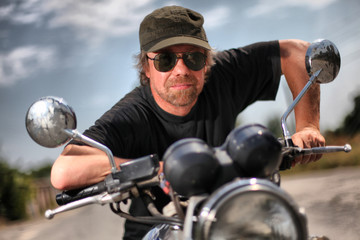 Fototapeta na wymiar Brutal white man in black glasses on motorcycle.