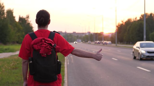 Hitchhiking man stand thumb up on roadside, try to catch car