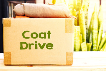 clothes in carton box on wood table for donation, coat drive concept 