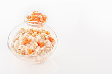 Oatmeal with pumpkin and nuts in a glass plate on a white background. Close-up. Copy space