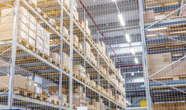 Large cardboard boxes on shelves closed metal mesh in a warehouse in an industrial enterprise. Warehouse technologies, employment at the factory. Arrangement of goods. Parcel delivery.